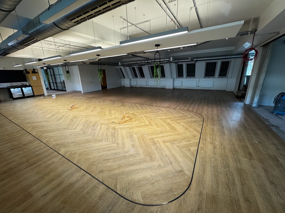 Große Bürofläche mit frisch verlegtem Vinylboden in Fischgrätmuster und sichtbaren Kabeln bei Vinylboden verlegen