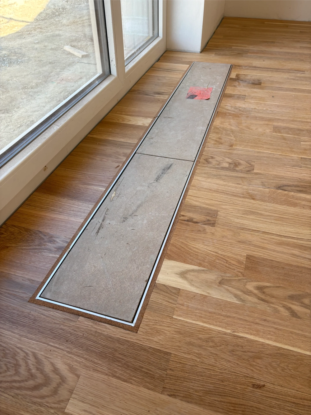 Abgedeckter Bodenausschnitt im Eichenparkett neben Glasschiebetür – Untergrund vorbereiten