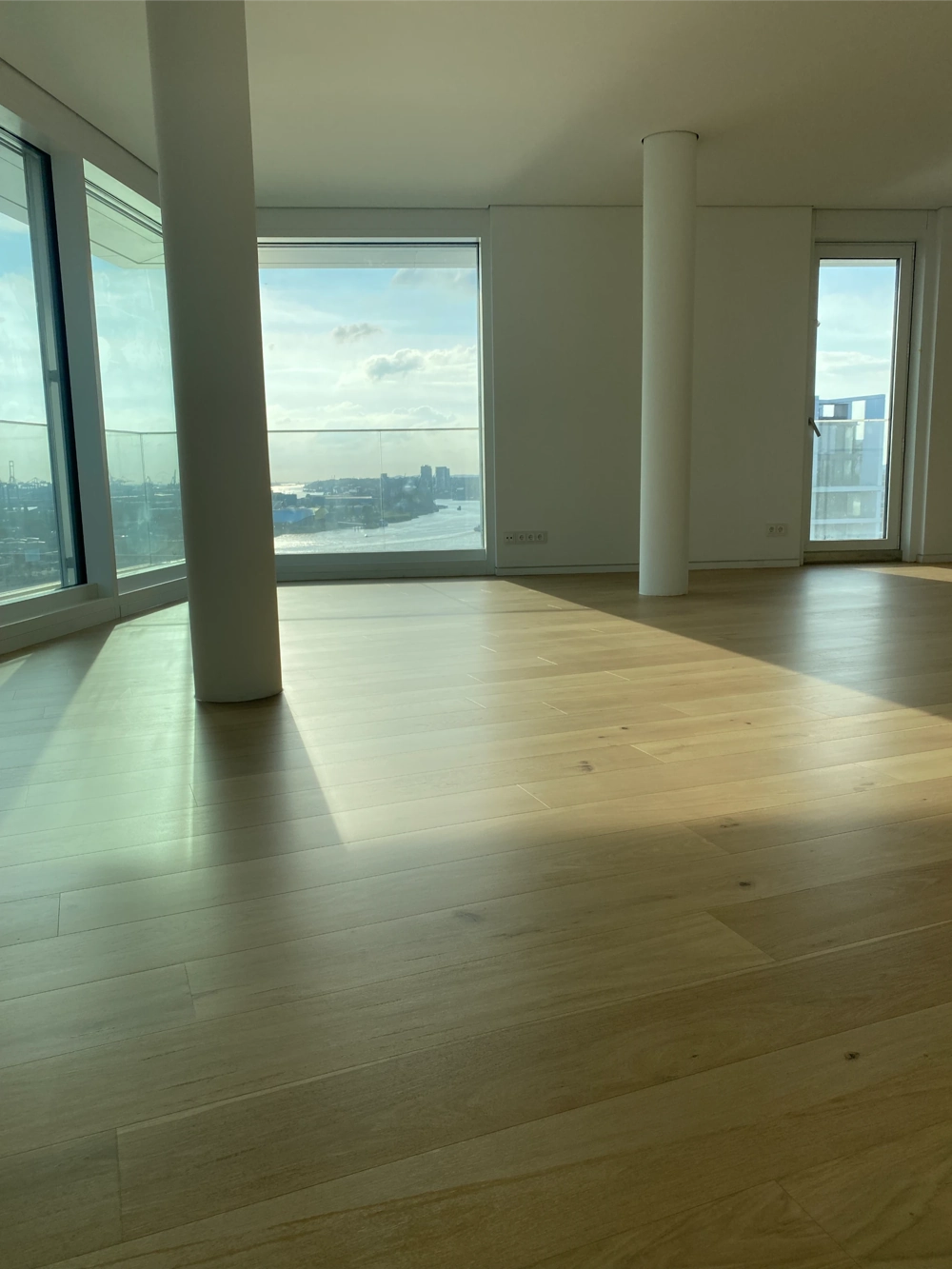Heller Raum mit neu verlegtem Eichendielen-Parkett, großen Panoramafenstern und freiem Blick aufs Wasser Parkett verlegen