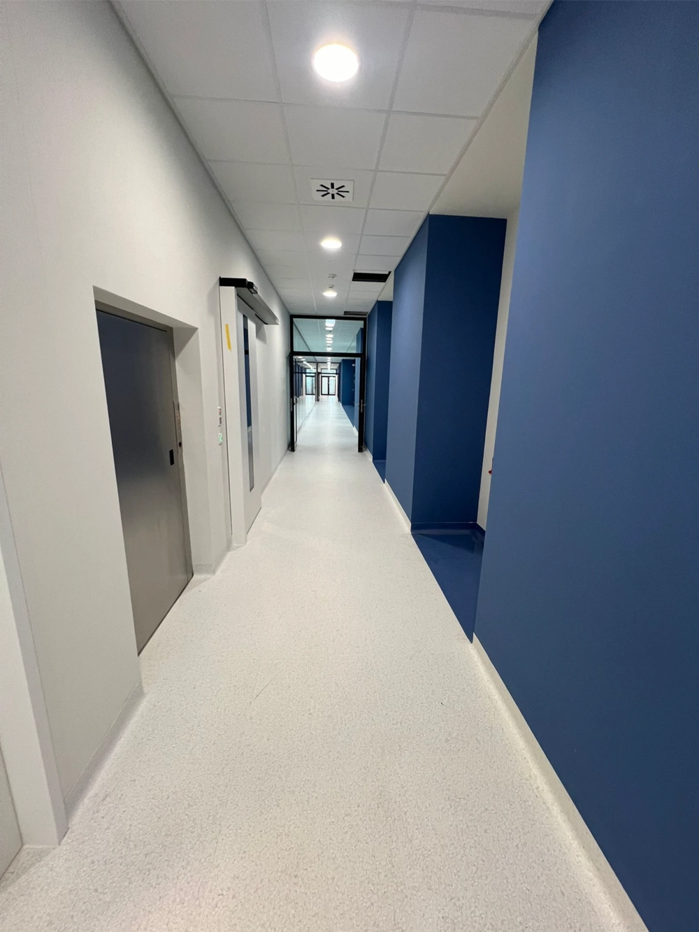 Korridor mit weißem Epoxidharzboden und blauen Wänden in einem gewerblichen Objekt