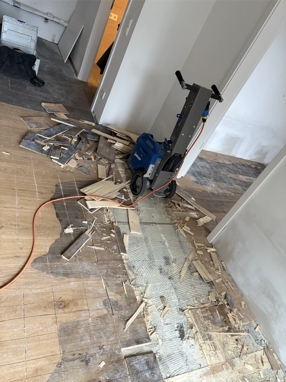 Professionelle Maschine beim Parkett entfernen: Holzplanken und Kleberreste auf vorbereitetem Unterboden