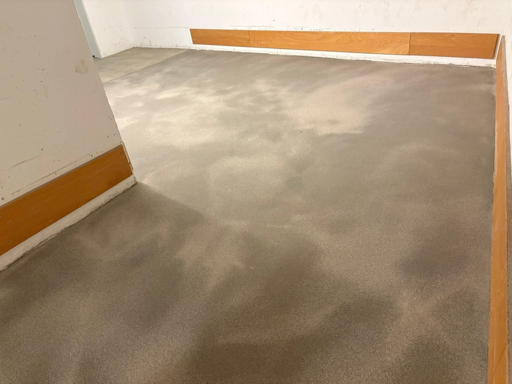 Gleichmäßig geglätteter Zementestrich in Raumecke nach Untergrund vorbereiten