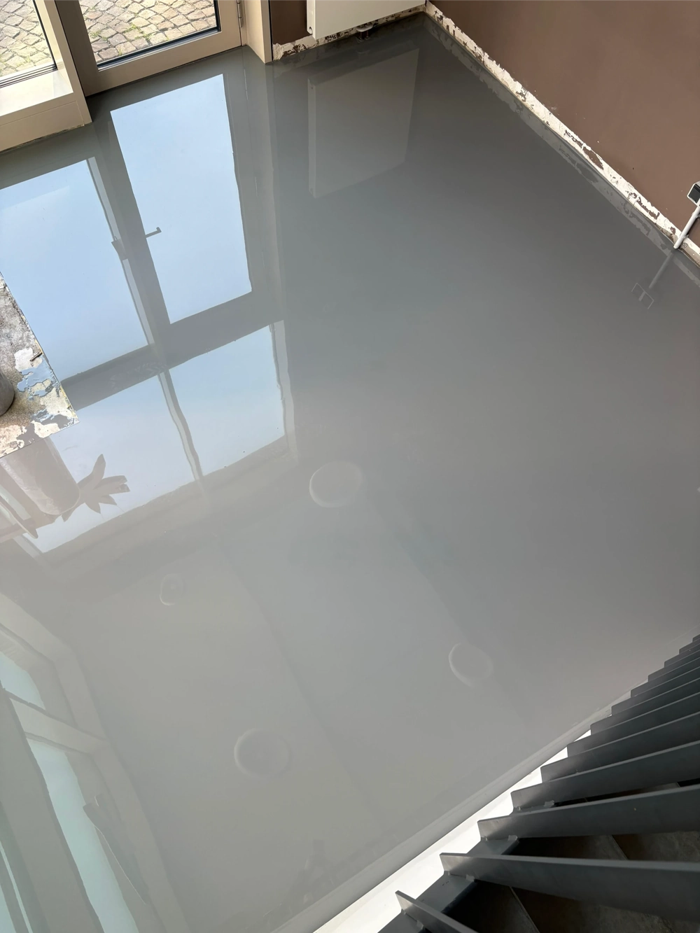 Glänzender, frisch verlegter Epoxidharzboden in einem Raum mit Fensterreflexion