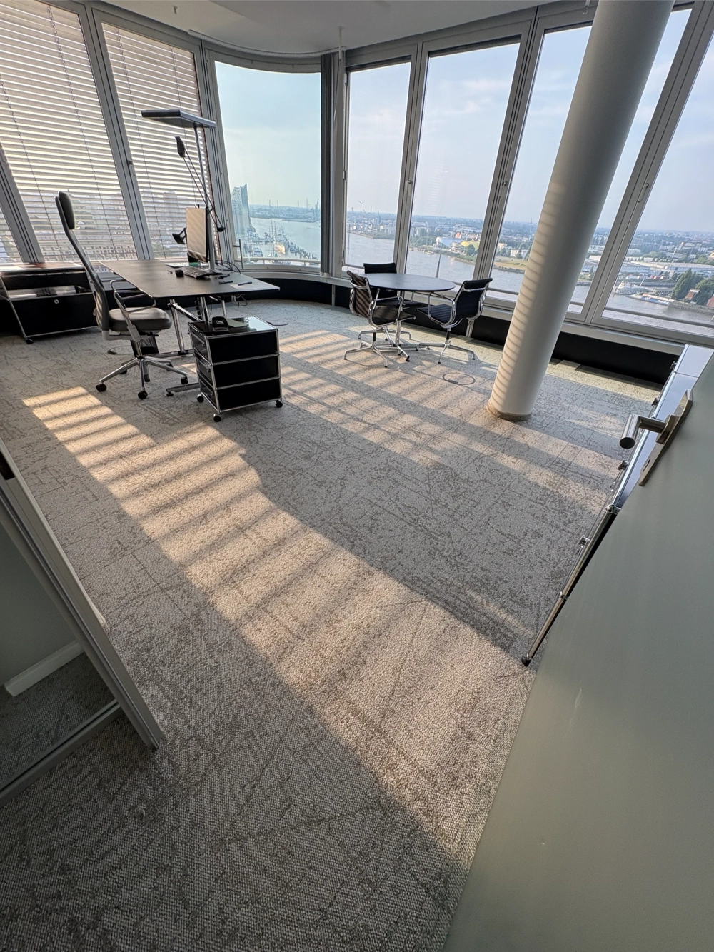 Büro mit großen Fensterfronten, Schreibtischen, Stühlen auf frisch verlegtem Teppichboden (Teppich verlegen)