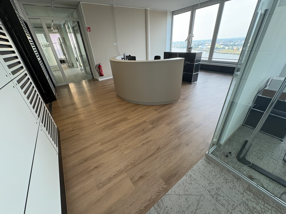 Neuer Vinylboden in modernem Büro mit Empfangstheke vor großen Fenstern