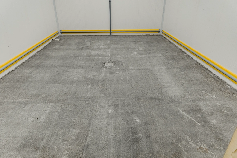 Raum mit freigelegtem Betonboden und Wandrohren für Untergrund vorbereiten